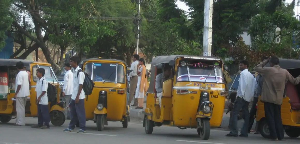 Yellow auto rickshaws carrying passengers along a Hyderabad road
