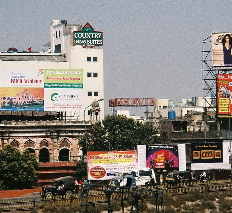 Stacked advertising hoardings and display boards above an Indian street